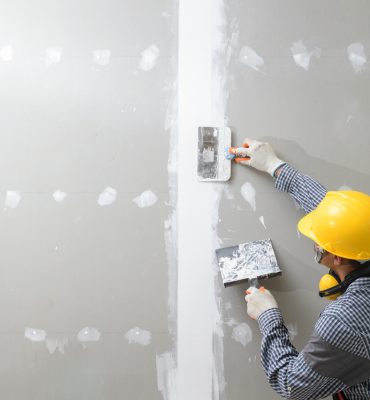 interior decoration construction furniture builtin.Plasterer in working uniform plastering the wall indoors.